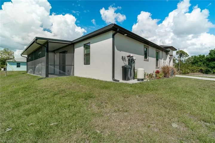 Rear view of house featuring a yard, stucco siding, and a sunroom