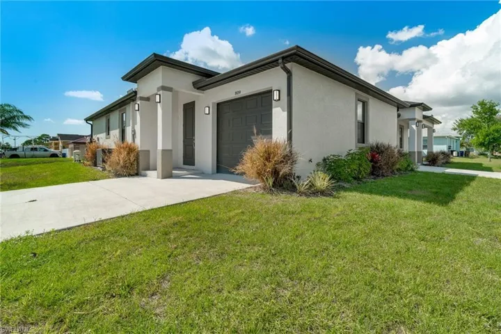 View of front of home featuring a front yard, stucco siding, an attached garage, and driveway