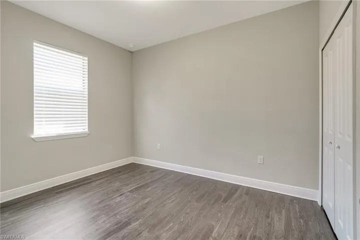Unfurnished bedroom featuring a closet and dark wood-style flooring