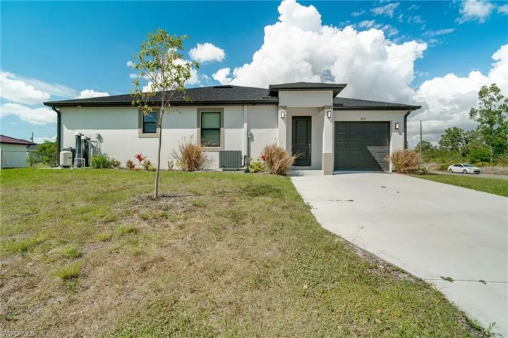 View of front facade with stucco siding, a front lawn, and a garage