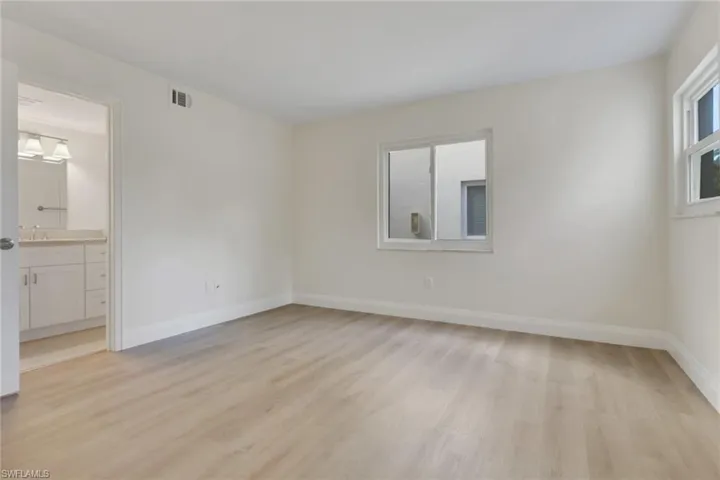 Unfurnished bedroom with light wood-style flooring and connected bathroom