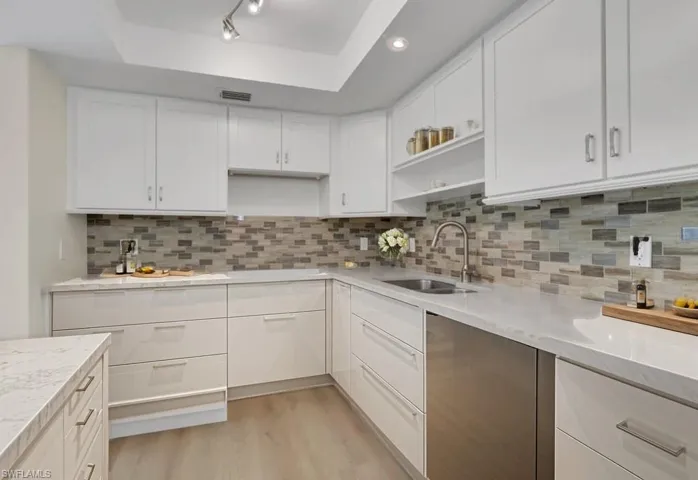 Kitchen staged with open shelves, white cabinetry, light wood-style flooring, tasteful backsplash, and light stone countertops