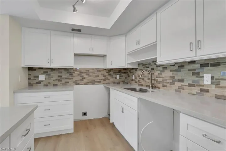 Kitchen with white cabinets, tasteful backsplash, and light stone counters
