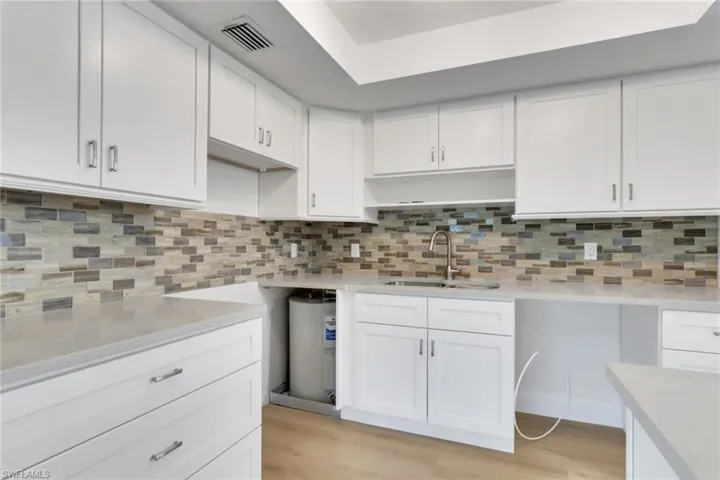 Kitchen featuring white cabinets, tasteful backsplash, and light wood-style flooring