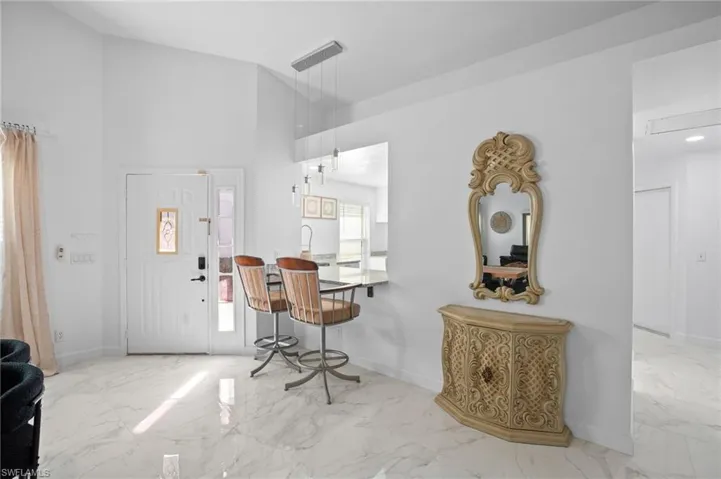Foyer entrance with light marble finish flooring and high vaulted ceiling