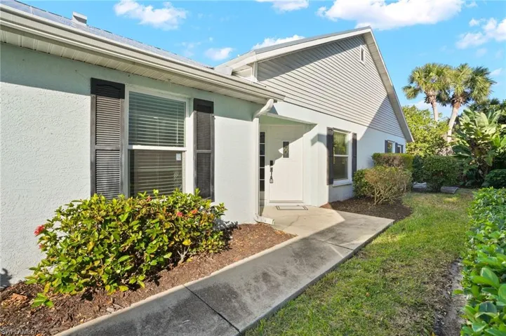 Property entrance with a yard and stucco siding