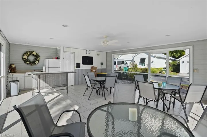 Dining area with a sunroom, wood walls, ceiling fan, and light tile patterned floors