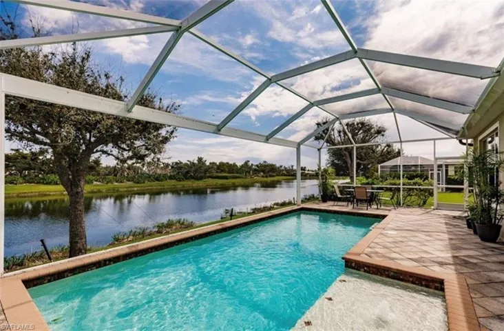 View of pool with a patio area, glass enclosure, and a water view