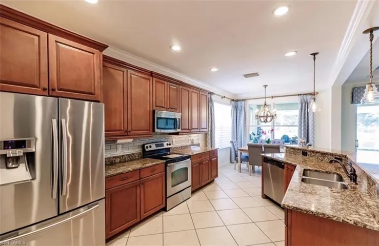 Kitchen with appliances with stainless steel finishes, pendant lighting, an inviting chandelier, and sink