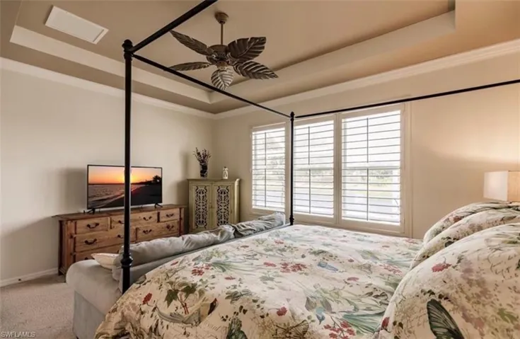 Bedroom featuring ornamental molding, a raised ceiling, ceiling fan, and carpet floors