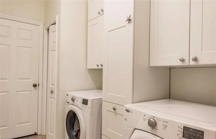 Clothes washing area featuring cabinets and separate washer and dryer