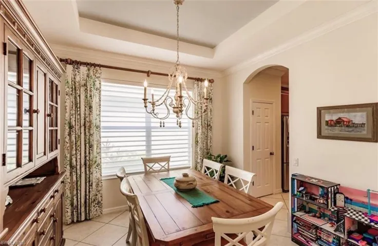 Dining space featuring crown molding, a raised ceiling, an inviting chandelier, and light tile patterned floors
