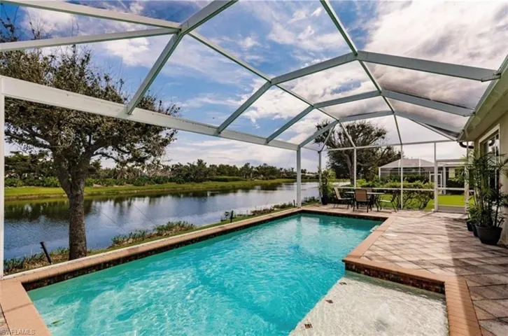 View of swimming pool with a lanai, a water view, and a patio