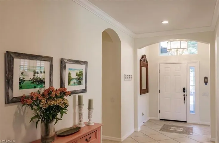 Foyer featuring light tile patterned floors, a chandelier, and crown molding