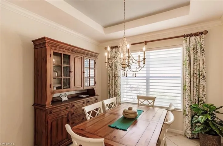 Tiled dining room with plenty of natural light, a raised ceiling, and crown molding