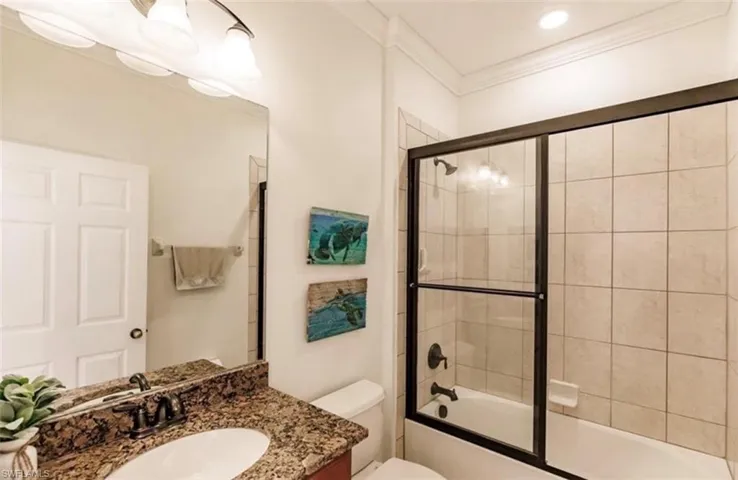 Full bathroom with crown molding, vanity, toilet, and enclosed tub / shower combo