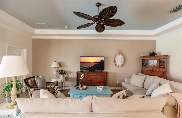 Living room with ornamental molding, a tray ceiling, and ceiling fan