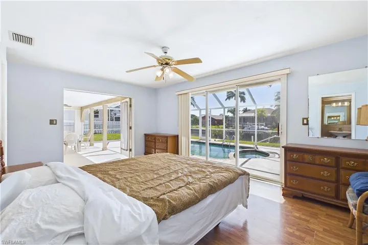 Bedroom featuring access to exterior, wood finished floors, ceiling fan, and a sunroom