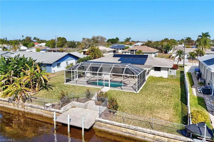 Rear view of property featuring a fenced backyard, a lanai, an outdoor pool, a residential view, and a sunroom