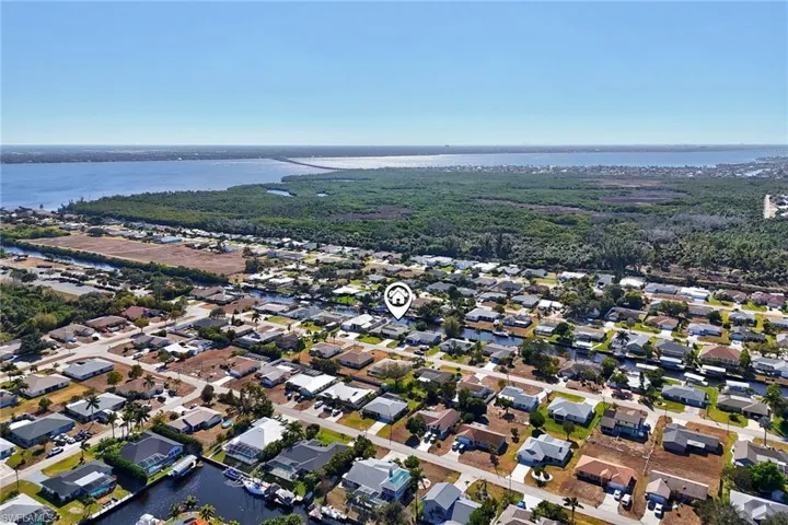 Aerial view of property and surrounding area featuring a nearby body of water and nearby suburban area