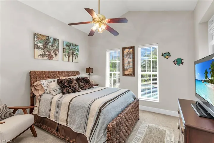 Bedroom with a ceiling fan, carpet, baseboards, and vaulted ceiling