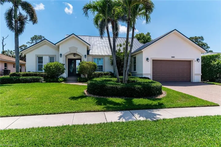 Ranch-style home featuring driveway, central air condition unit, stucco siding, a front lawn, and a garage