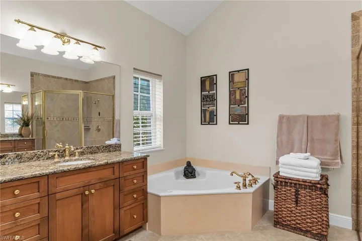 Full bathroom featuring tile patterned flooring, vanity, vaulted ceiling, a stall shower, and a bath