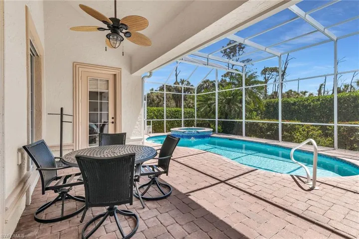 View of pool featuring glass enclosure, a pool with connected hot tub, a ceiling fan, and a patio area