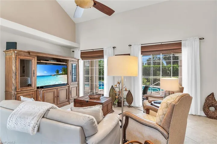 Living room featuring light tile patterned floors, lofted ceiling, and a ceiling fan