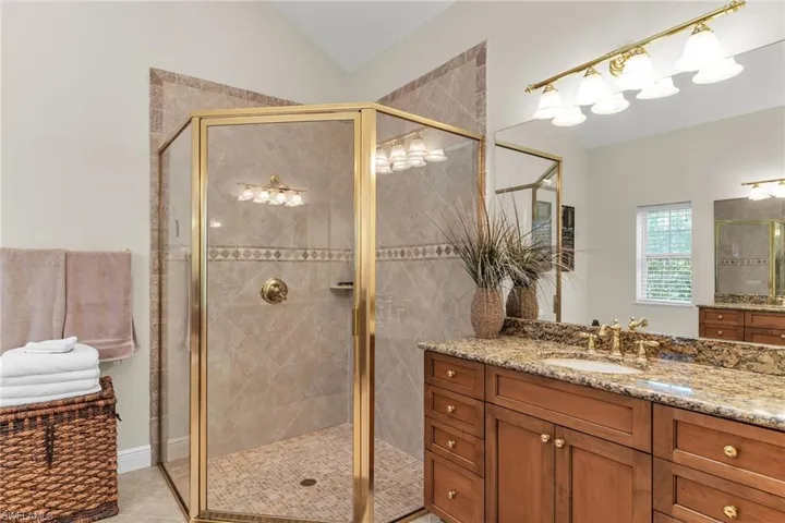Bathroom featuring tile patterned floors, vanity, a stall shower, and lofted ceiling