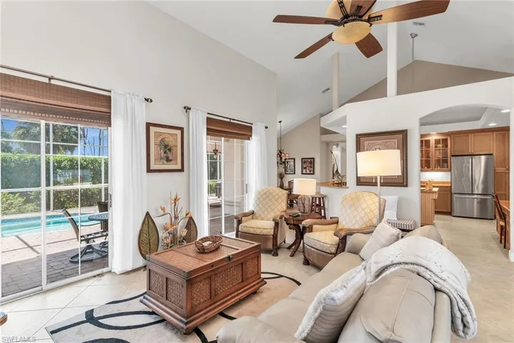 Living room with light tile patterned flooring, plenty of natural light, arched walkways, and a ceiling fan