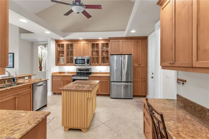 Kitchen with recessed lighting, a ceiling fan, appliances with stainless steel finishes, a sink, and a tray ceiling