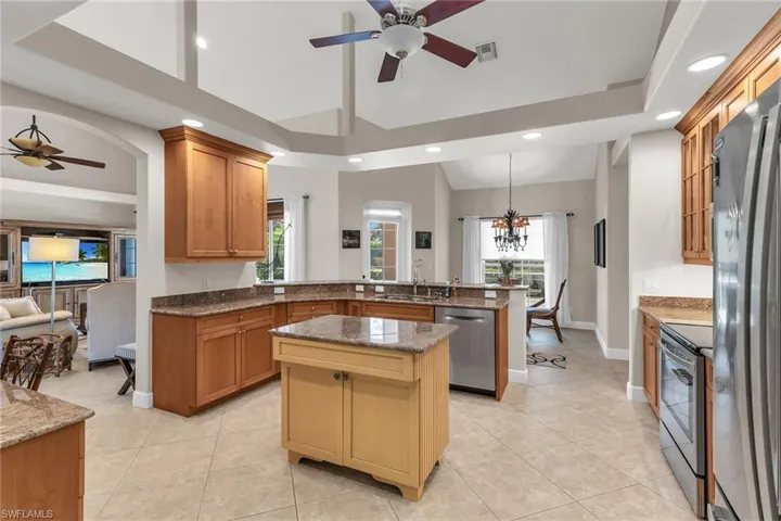 Kitchen with a kitchen island, a ceiling fan, a peninsula, stainless steel appliances, and visible vents