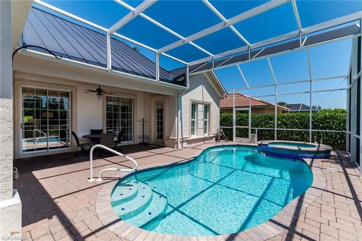 View of pool with glass enclosure, ceiling fan, a pool with connected hot tub, and a patio area