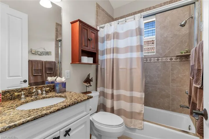 Bathroom featuring shower / tub combo with curtain, toilet, and vanity