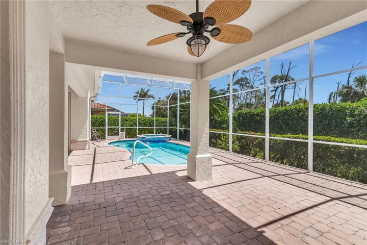 View of swimming pool with ceiling fan, a lanai, a pool with connected hot tub, and a patio area