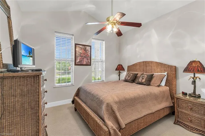 Carpeted bedroom featuring baseboards, lofted ceiling, and a ceiling fan