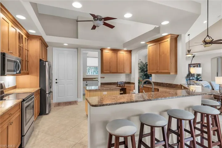 Kitchen with stainless steel appliances, dark stone countertops, a breakfast bar, and ceiling fan