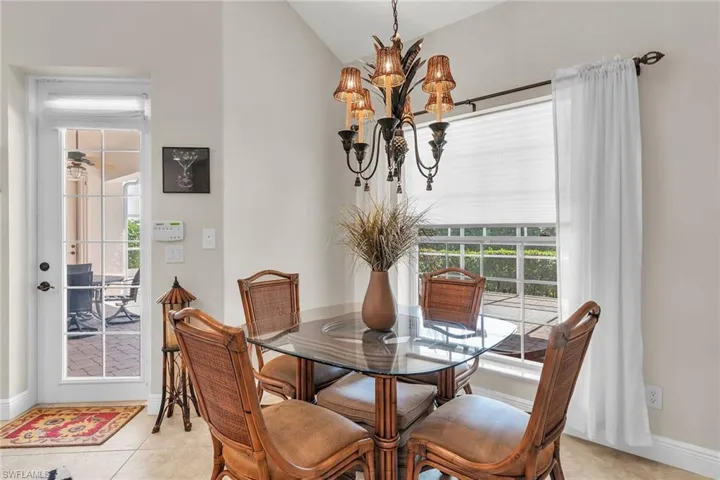 Dining space with baseboards, a notable chandelier, lofted ceiling, and light tile patterned floors