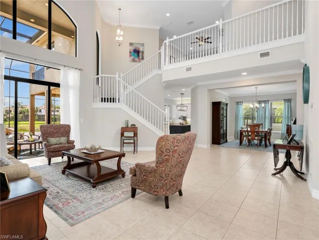 Grand living room with soaring ceilings, expansive two-story windows, and tile flooring