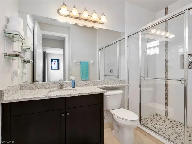 Bathroom featuring a dark wood vanity with a light speckled countertop, under-mount sink, and large wall-mounted mirror