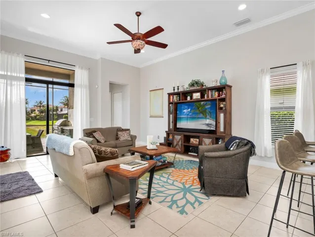 Expansive living area featuring light-toned tile flooring throughout and a ceiling fan with integrated lighting