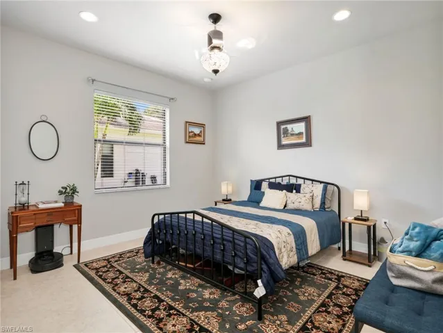 Spacious guest suite bedroom featuring recessed lighting, a ceiling fan with integrated light, tile flooring, and a large window with horizontal blinds
