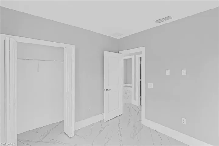 Unfurnished bedroom featuring light marble finish flooring and a closet