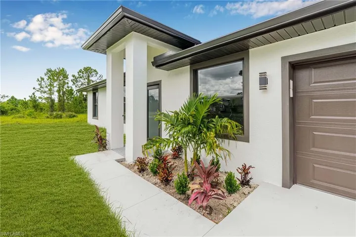 Doorway to property featuring stucco siding and a lawn