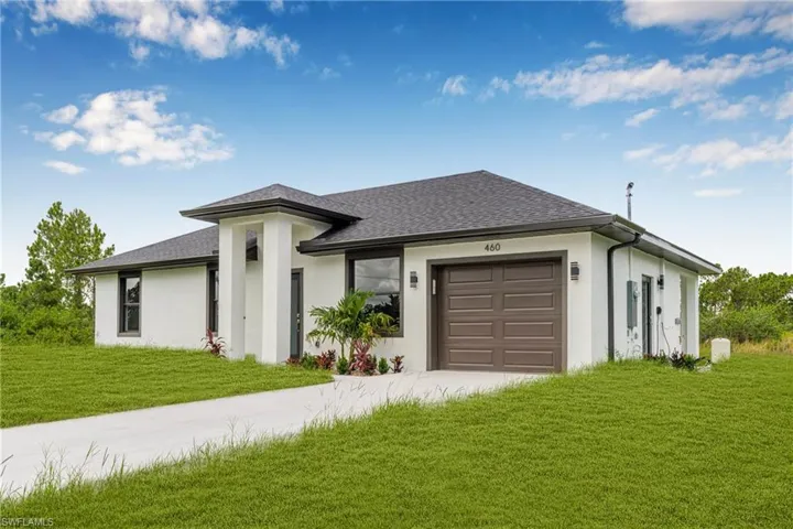 Prairie-style home featuring a garage, roof with shingles, driveway, and stucco siding