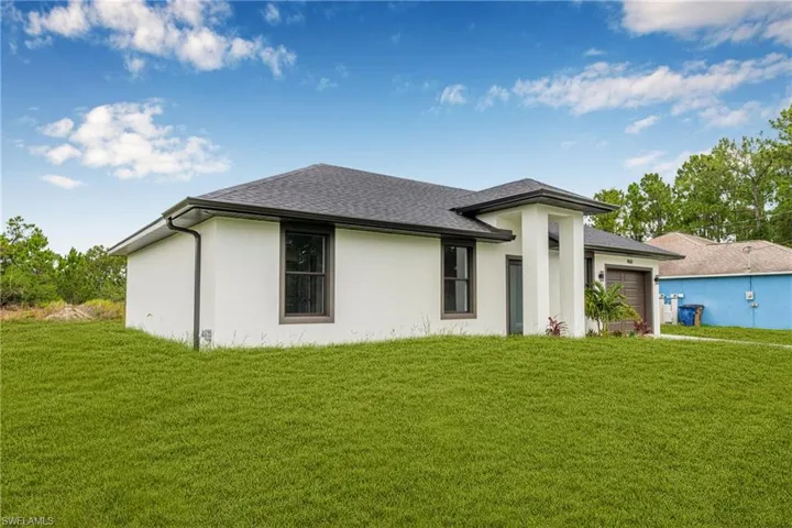Prairie-style home with a garage, a front yard, stucco siding, and roof with shingles