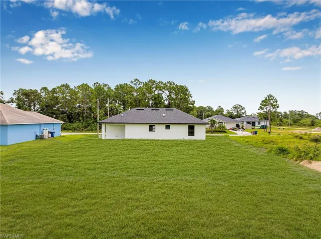 Rear view of house featuring a yard and view of scattered trees