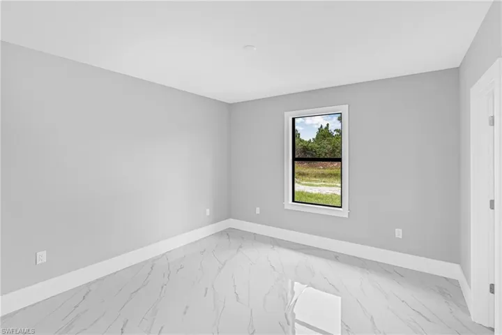 Spare room with light marble finish flooring and baseboards