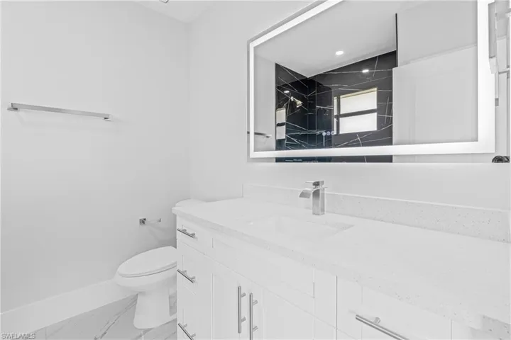 Full bath featuring vanity, marble look tile flooring, and a shower